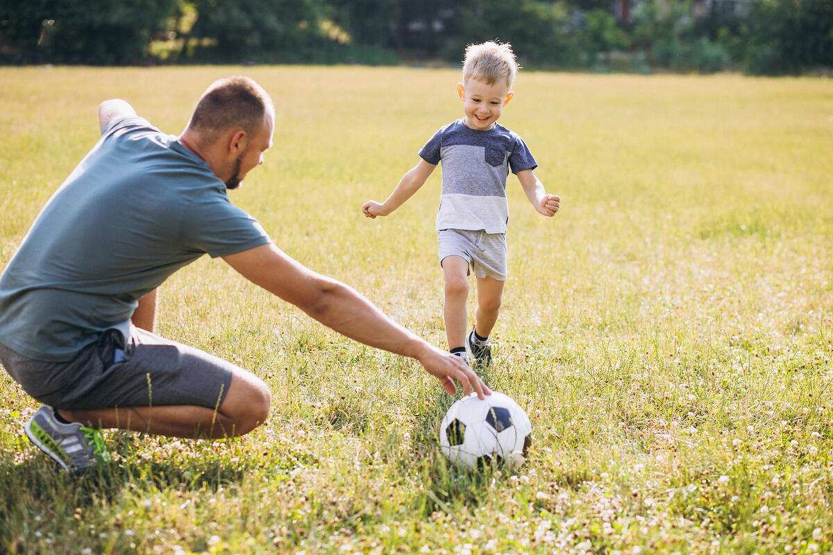 father-with-son-playing-football-field