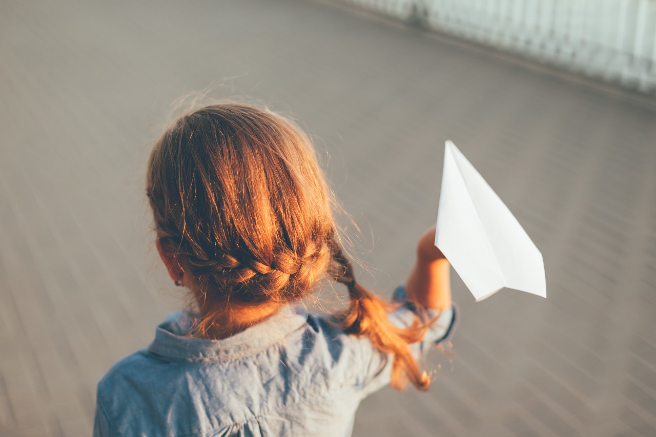 girl-playing-giwith-toy-paper-airplane.